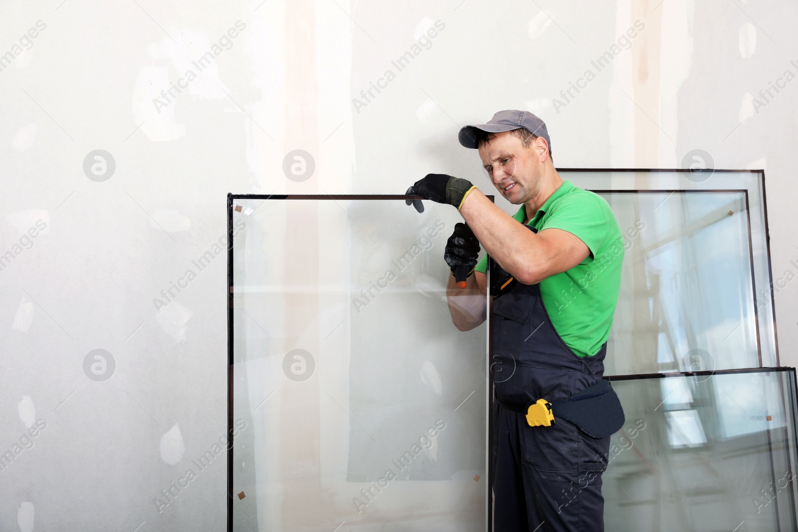 Photo of Worker in uniform preparing double glazing window for installation indoors