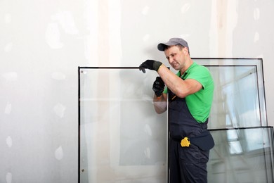 Worker in uniform preparing double glazing window for installation indoors