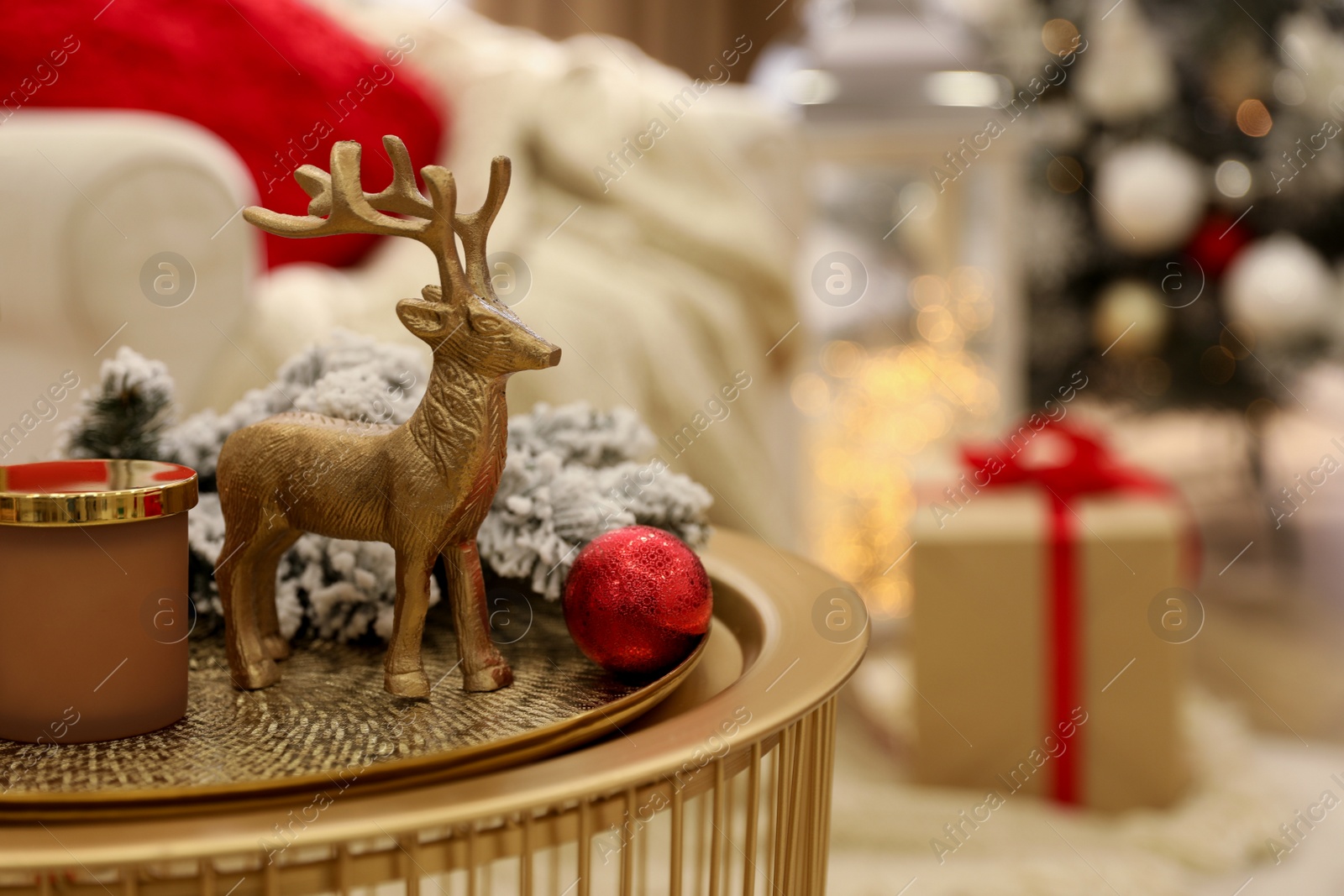 Photo of Christmas composition with decorative reindeer on golden table in room, closeup. Space for text