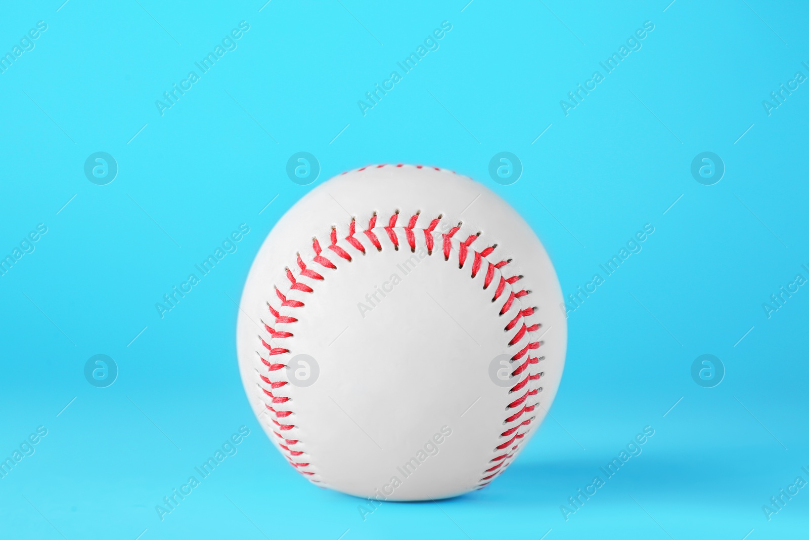 Photo of Baseball ball on light blue background, closeup. Sports game