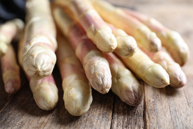 Photo of Pile of fresh white asparagus on wooden table, closeup