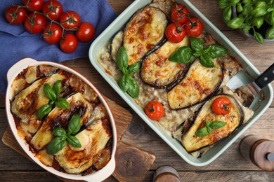 Photo of Delicious eggplant lasagna in baking dishes on wooden table, flat lay