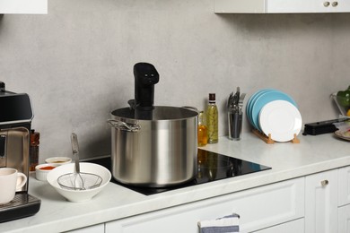 Photo of Pot with sous vide cooker in kitchen. Thermal immersion circulator