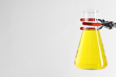 Photo of Retort stand and laboratory flask with liquid on white background, closeup. Space for text