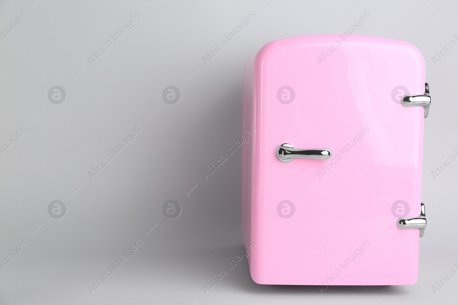 Photo of Cosmetic refrigerator on light background, space for text