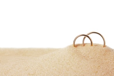 Photo of Honeymoon concept. Two golden rings and sand isolated on white