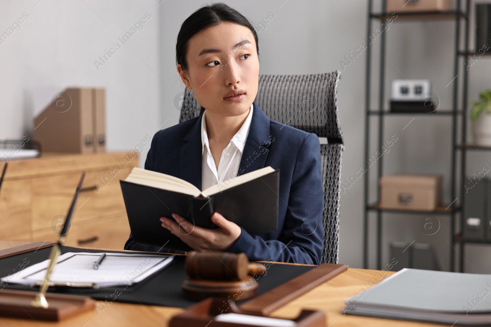 Photo of Notary reading book at table in office