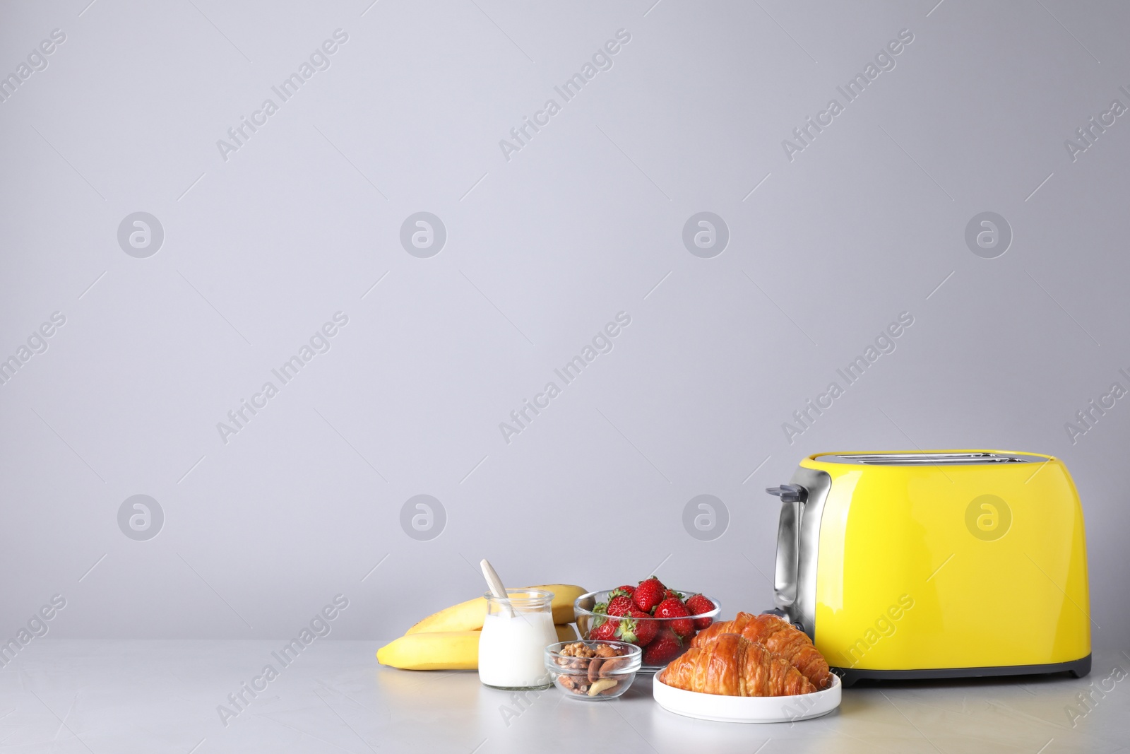 Photo of Healthy breakfast and modern toaster on light grey table, space for text