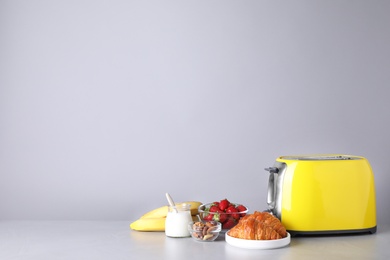 Photo of Healthy breakfast and modern toaster on light grey table, space for text