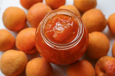 Photo of Jar of delicious jam and fresh ripe apricots on white background. Fruit preserve