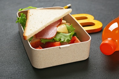 Lunch box with tasty sandwich on table