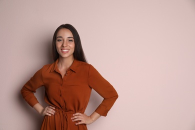 Young woman wearing stylish dress on pale pink background. Space for text