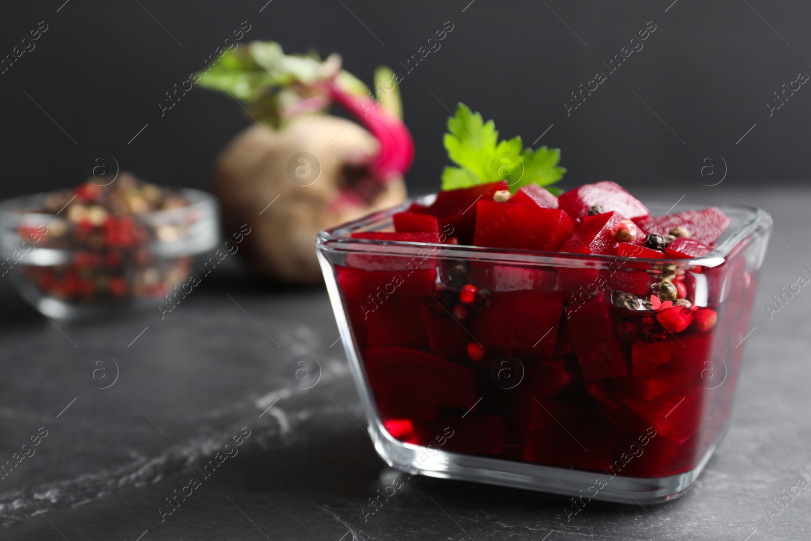 Photo of Pickled beets in glass bowl on dark marble table
