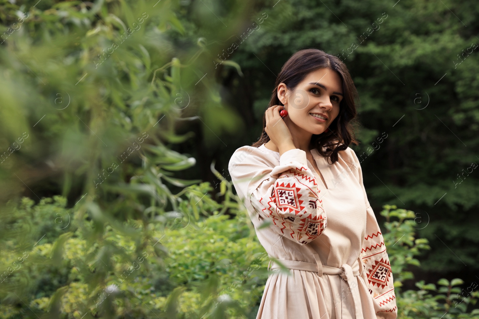 Photo of Beautiful woman wearing embroidered dress in countryside, space for text. Ukrainian national clothes