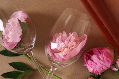 Photo of Bottle of rose wine, glasses and beautiful pink peonies on brown background, closeup