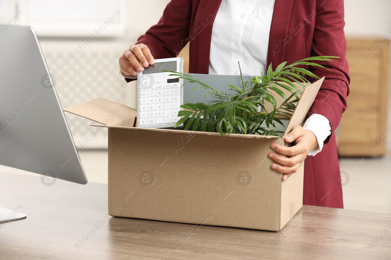 Photo of Unemployment problem. Woman with box of personal belongings at table in office, closeup