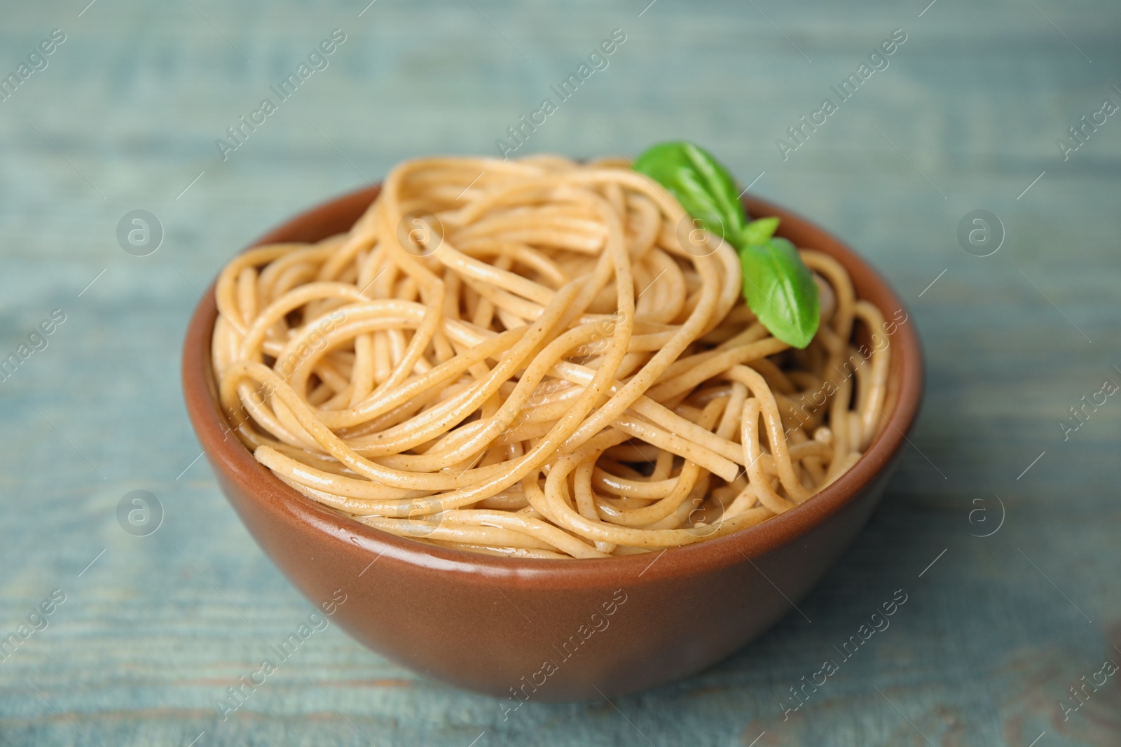 Photo of Tasty buckwheat noodles in bowl on blue wooden table