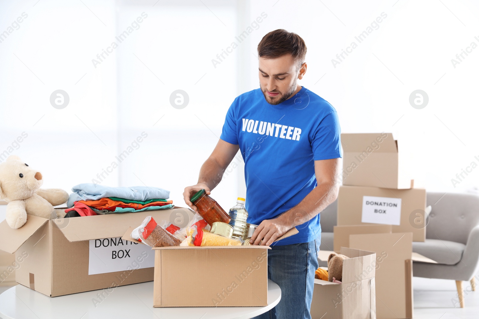 Photo of Male volunteer collecting donations at table indoors