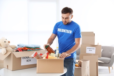 Photo of Male volunteer collecting donations at table indoors