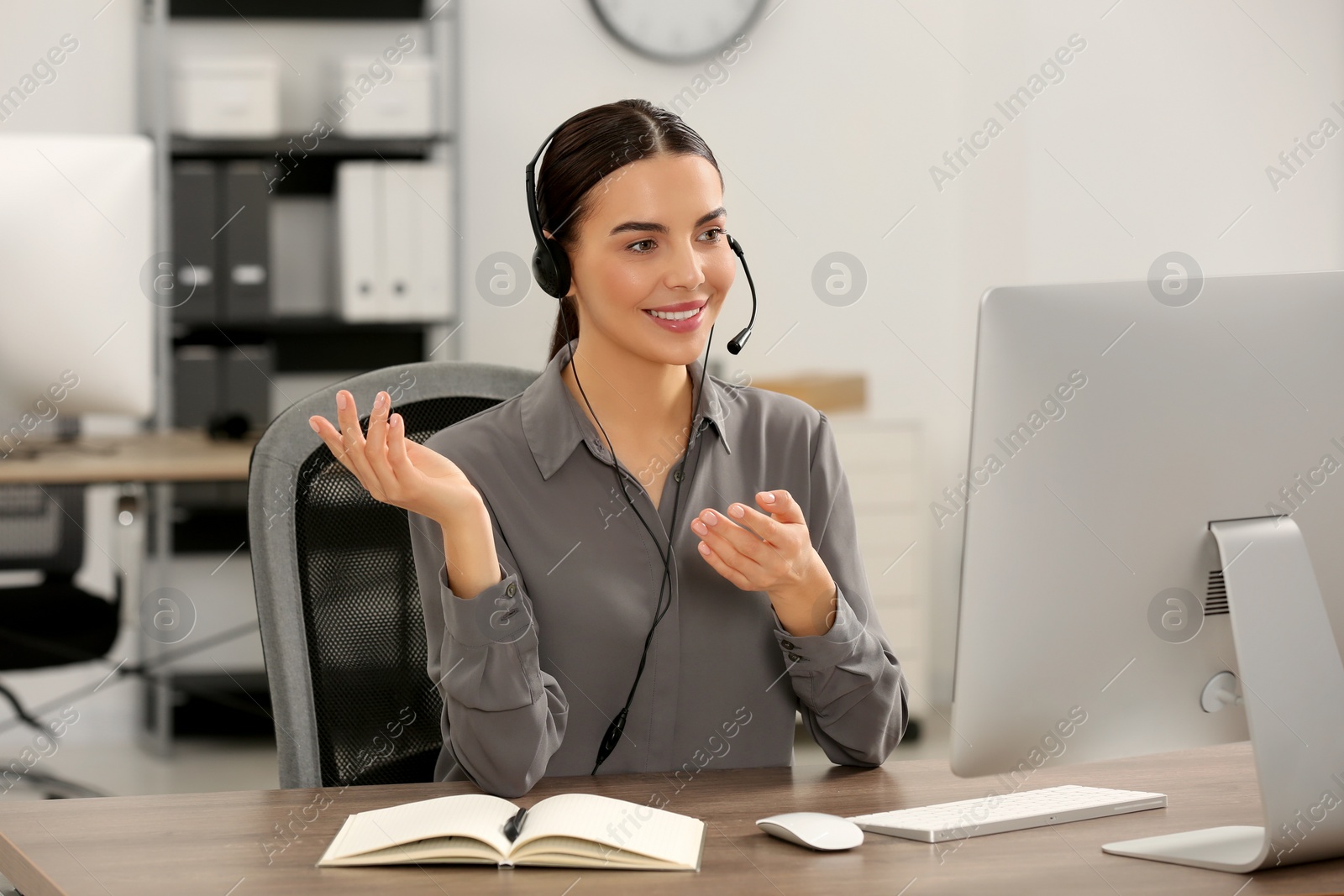 Photo of Hotline operator with headset working on computer in office