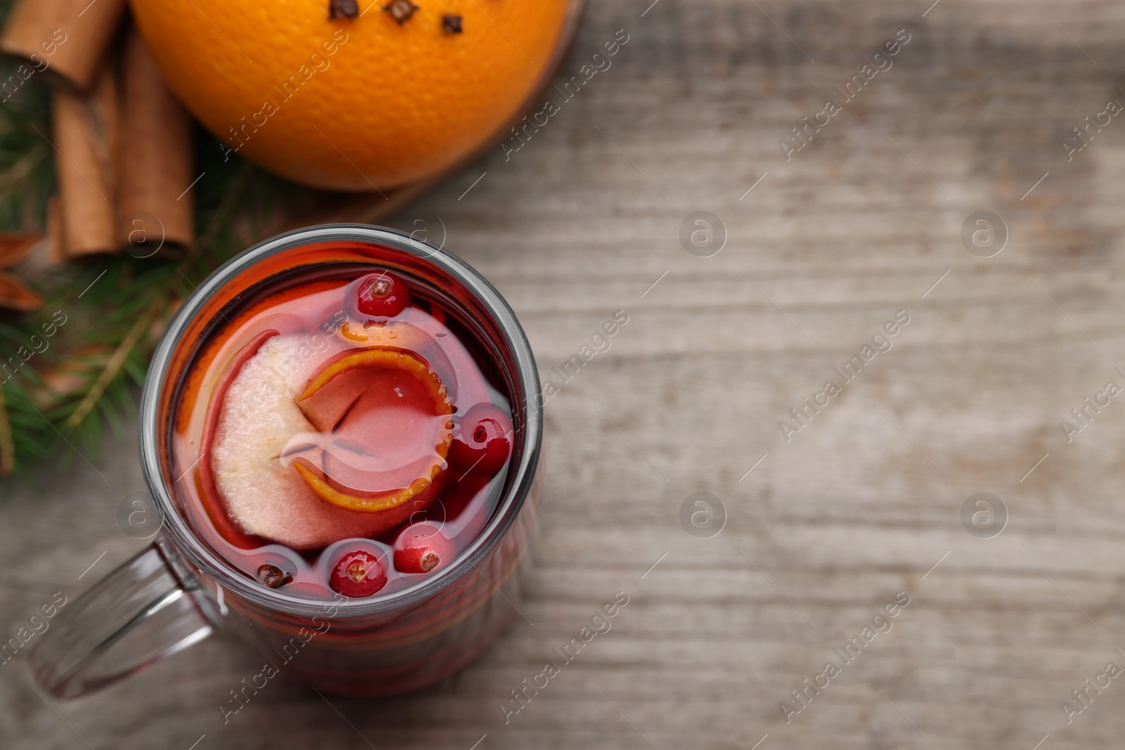 Photo of Aromatic mulled wine in glass cup on wooden table, above view. Space for text