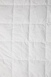 Photo of Soft quilted blanket as background, top view