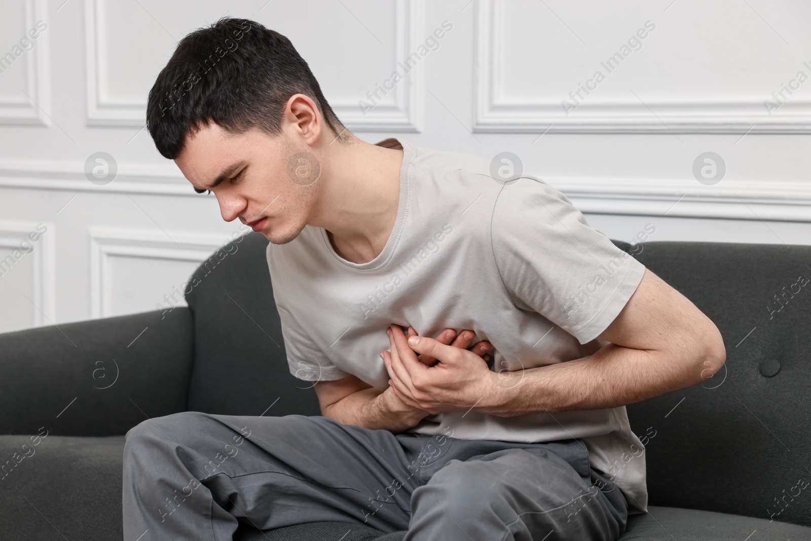 Photo of Young man suffering from heart hurt on sofa at home