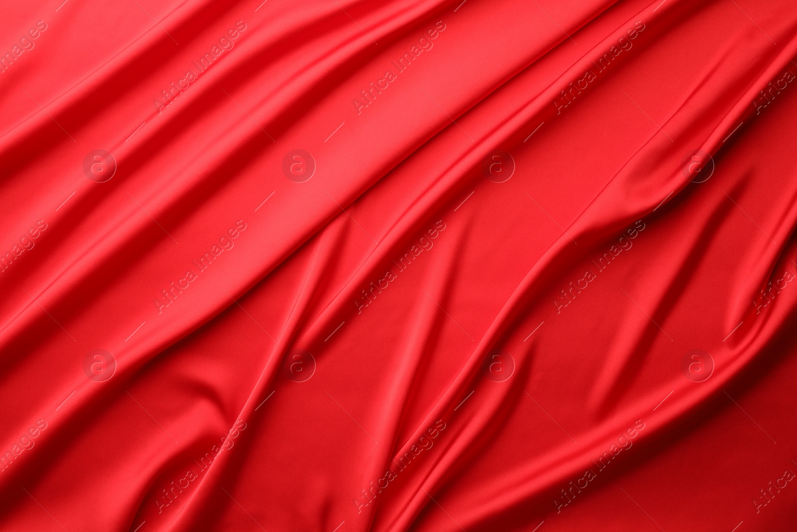 Photo of Crumpled red silk fabric as background, top view