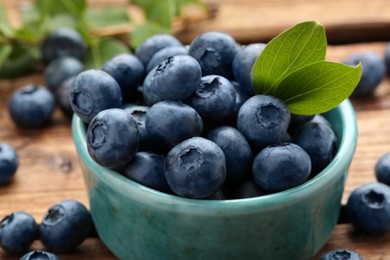 Photo of Tasty fresh blueberries and green leaves on table, closeup