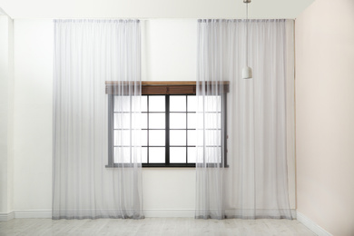 Photo of Window with beautiful curtains and open blinds in empty room