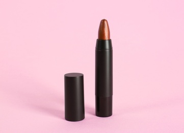 Photo of Bright lipstick in black tube on pink background