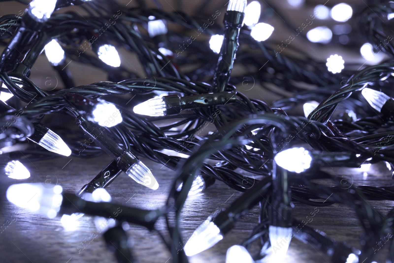 Photo of Beautiful Christmas lights on wooden table, closeup