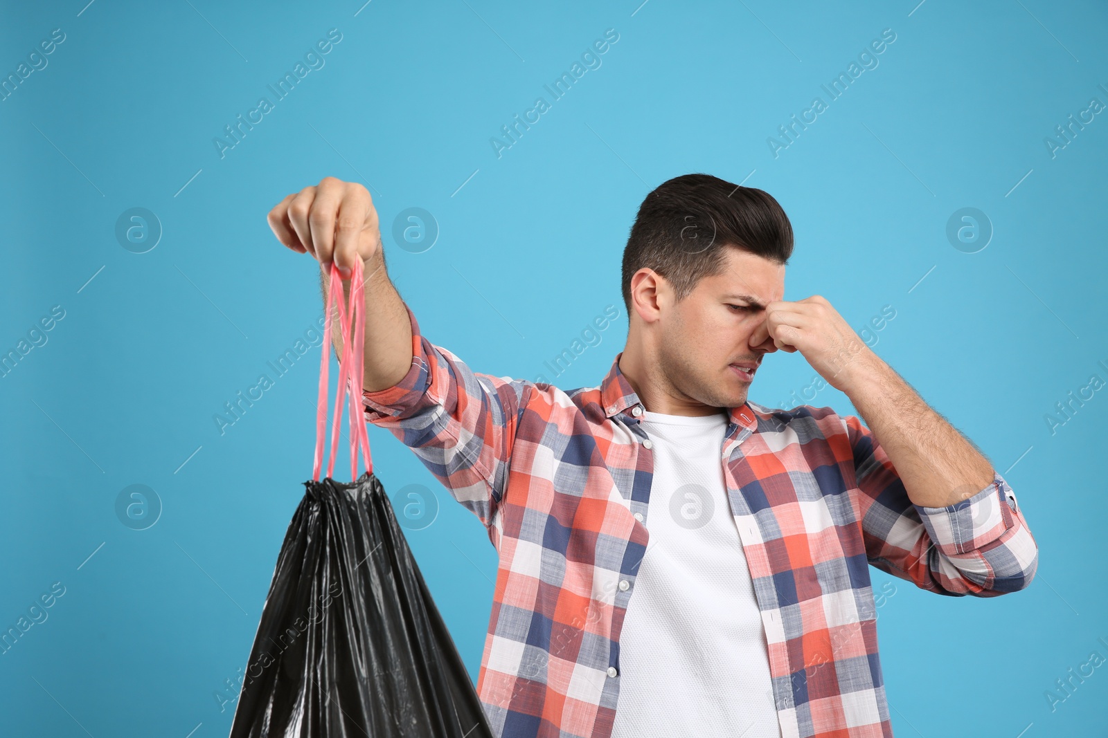 Photo of Man holding full garbage bag on light blue background