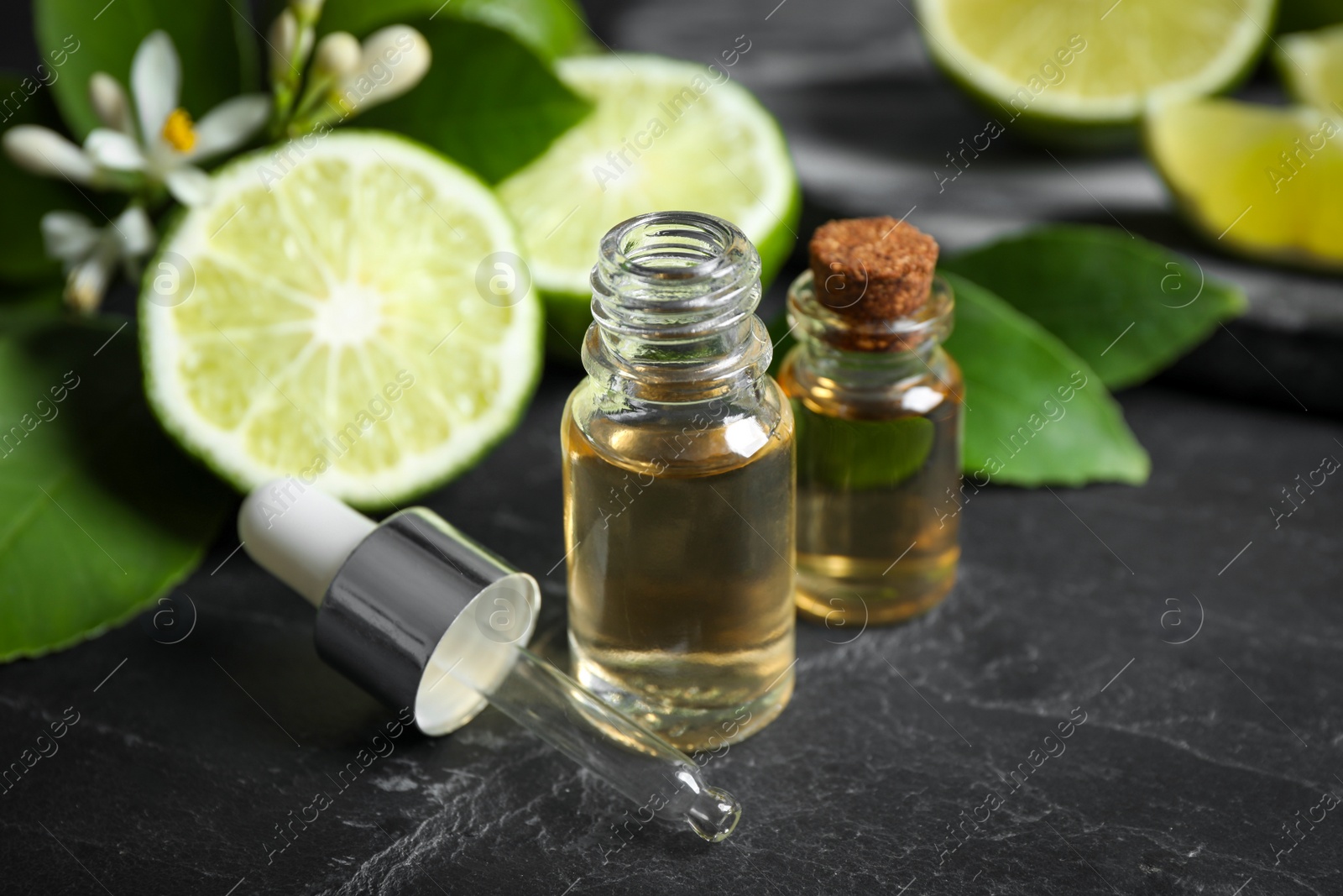 Photo of Bottles of citrus essential oil on black table