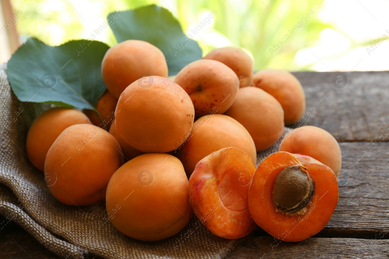 Photo of Delicious ripe apricots with napkin on wooden table, closeup