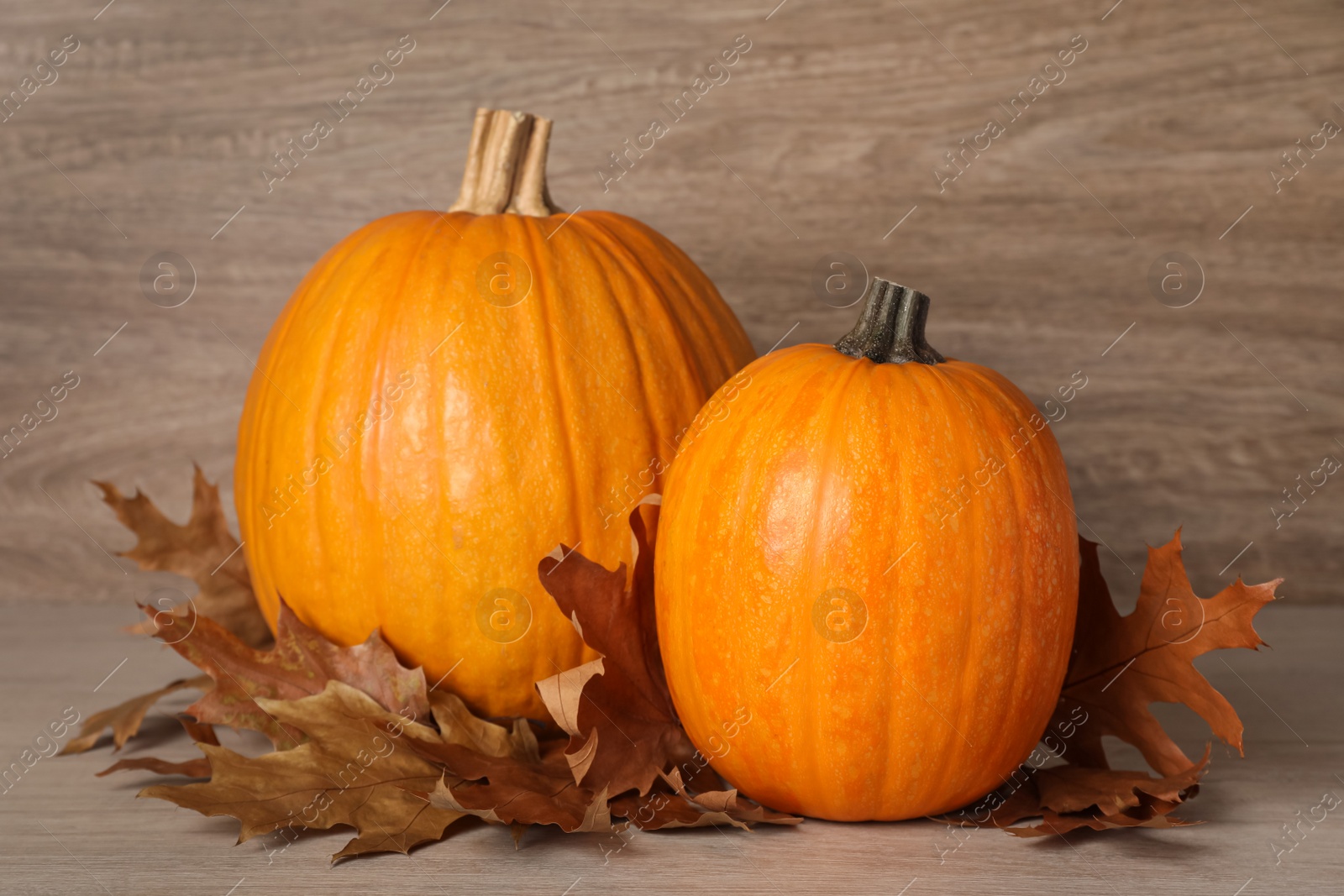 Photo of Fresh ripe pumpkins and dry leaves on wooden table