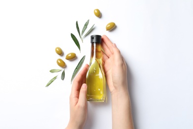 Photo of Woman holding bottle with oil and ripe olives on white background