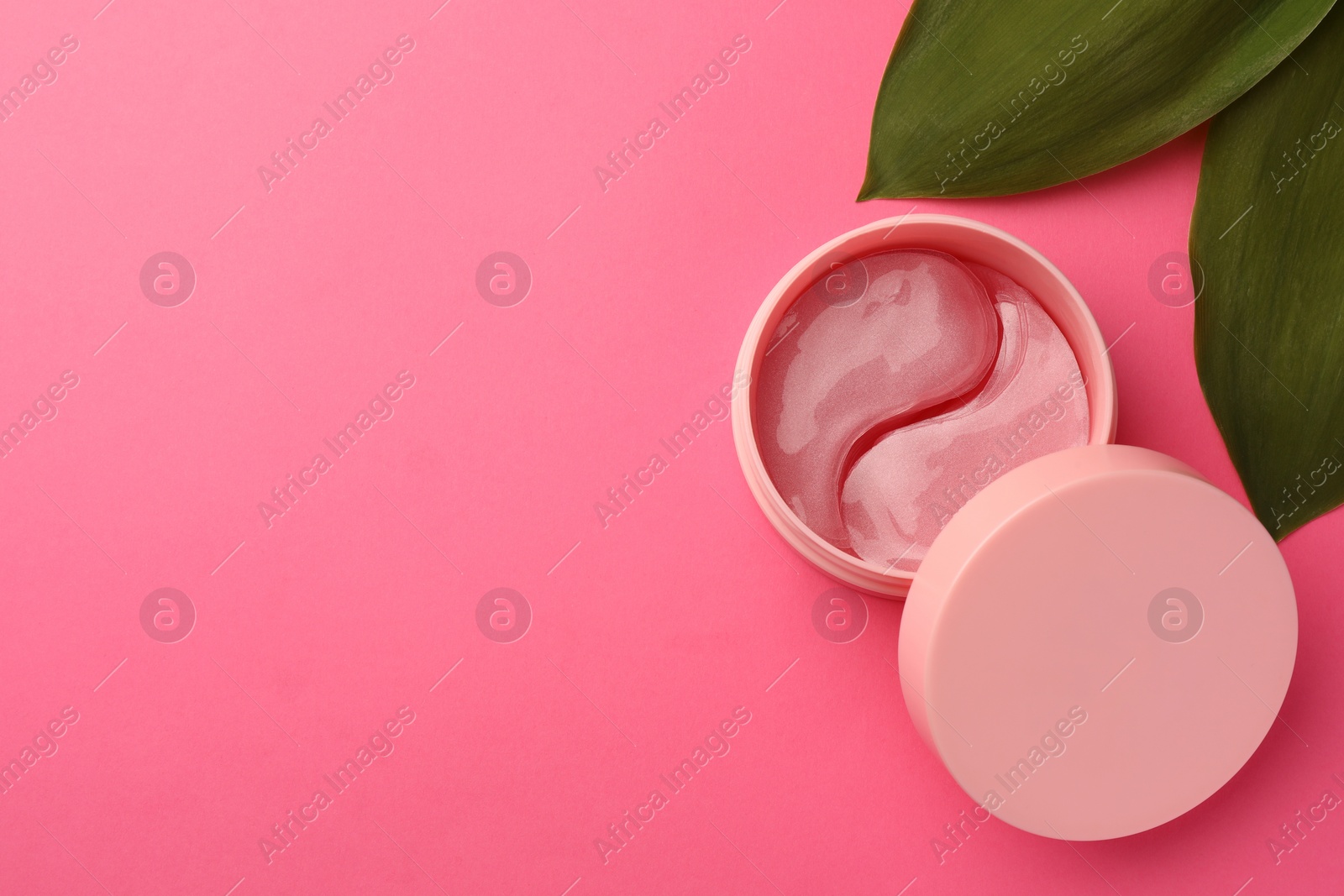 Photo of Jar of under eye patches and green leaves on pink background, flat lay with space for text. Cosmetic product