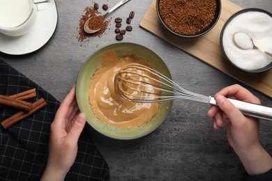 Photo of Woman whipping cream for dalgona coffee at gray table, top view