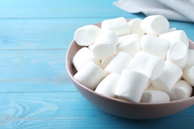 Photo of Delicious puffy marshmallows on light blue wooden table, closeup