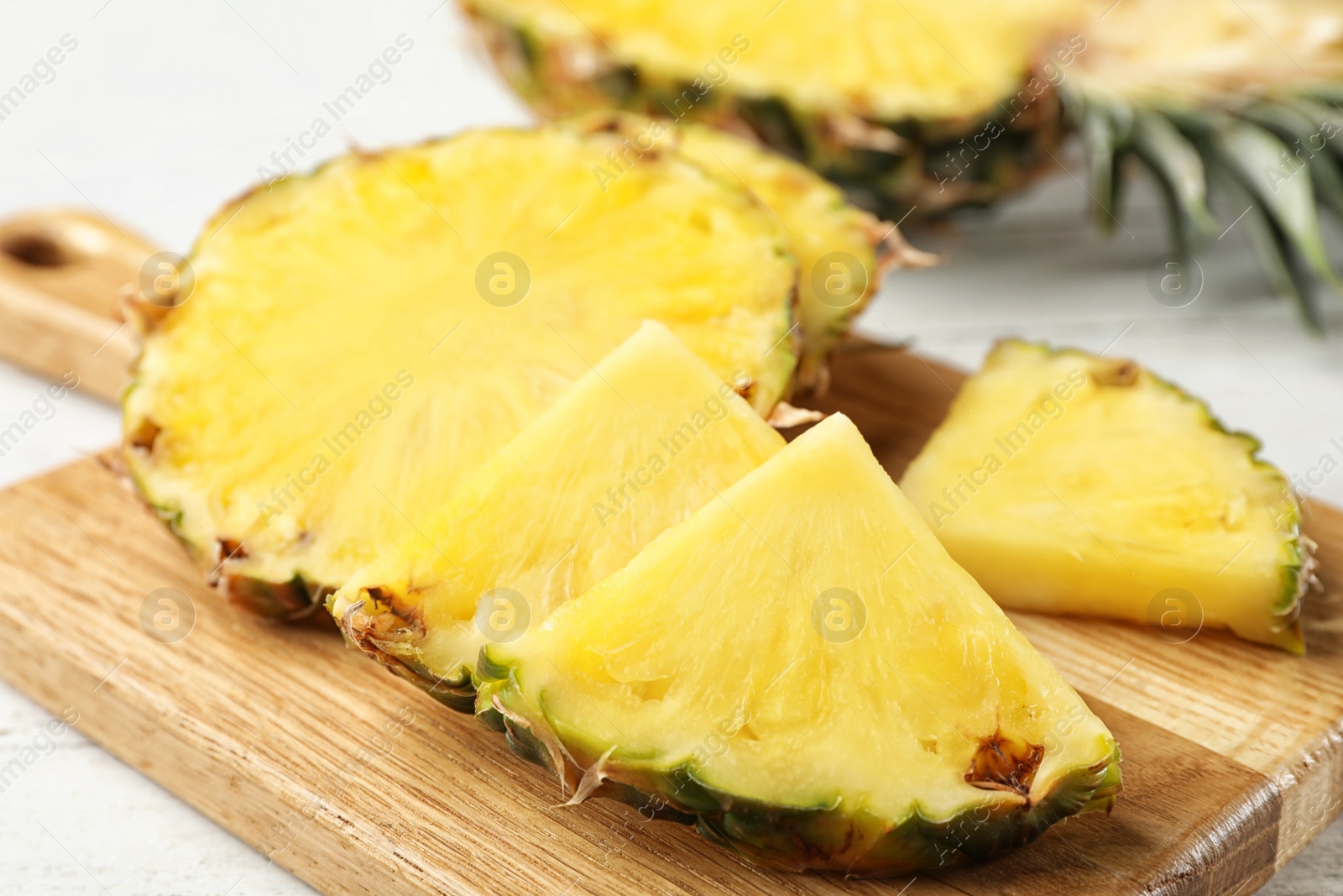 Photo of Cut fresh juicy pineapple on wooden board, closeup