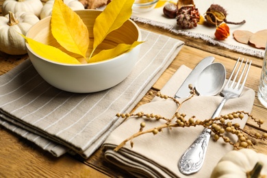 Photo of Seasonal table setting with fallen leaves and other autumn decor on wooden background