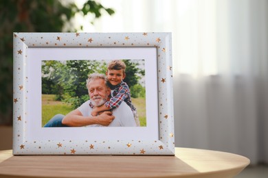 Photo of Framed family photo on wooden table in room. Space for text
