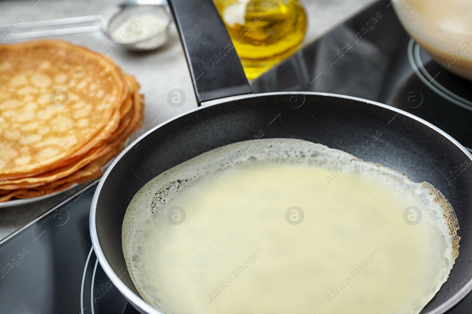 Photo of Delicious thin pancake in frying pan on induction stove, closeup