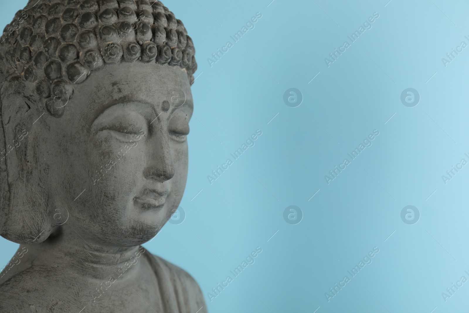 Photo of Beautiful stone Buddha sculpture on light blue background. Space for text