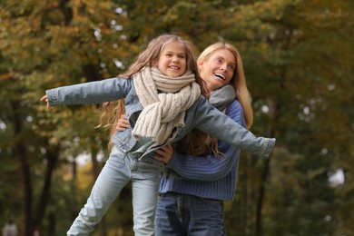 Photo of Happy mother playing with her daughter in autumn park