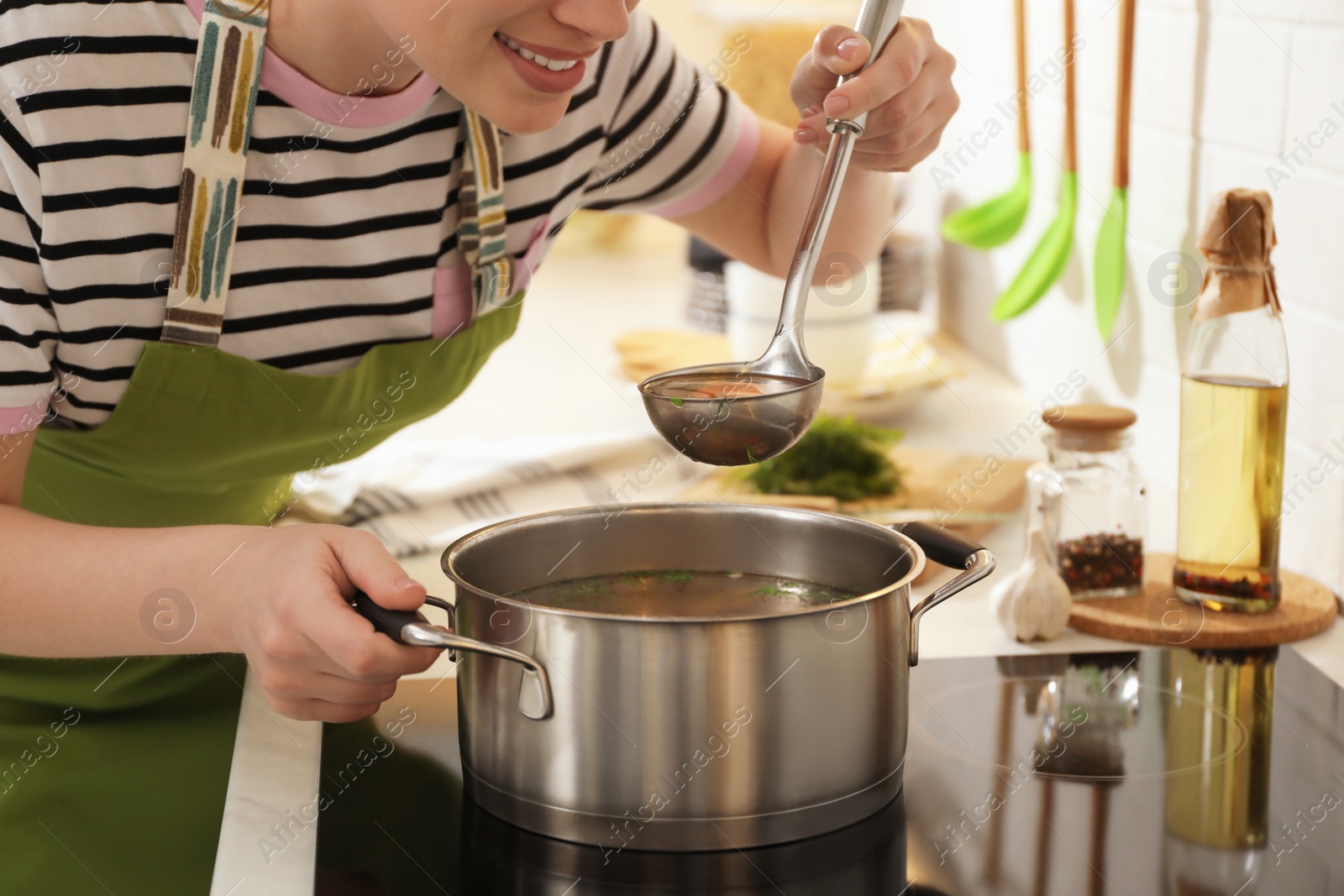 Photo of Woman making bouillon on stove in kitchen, closeup. Homemade recipe