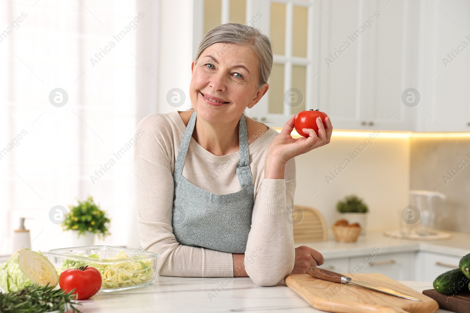 Photo of Happy housewife at white marble table in kitchen