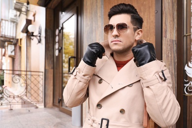 Handsome stylish man wearing black leather gloves outdoors. Space for text