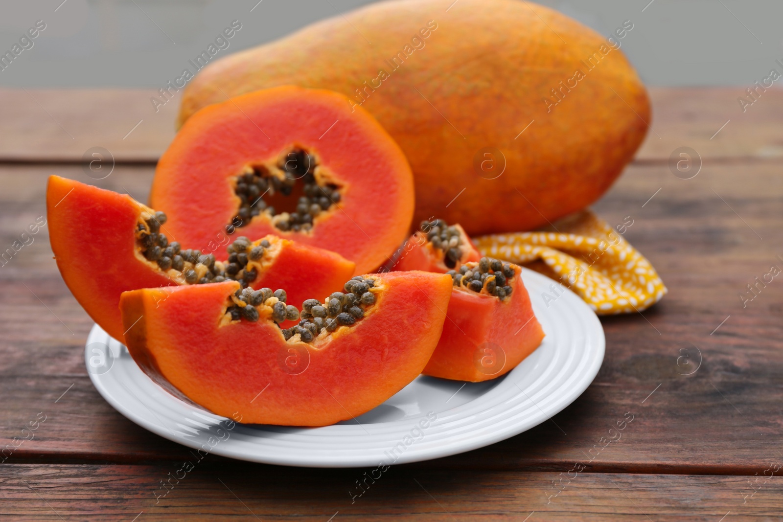 Photo of Ripe cut and whole papaya fruits on wooden table, closeup